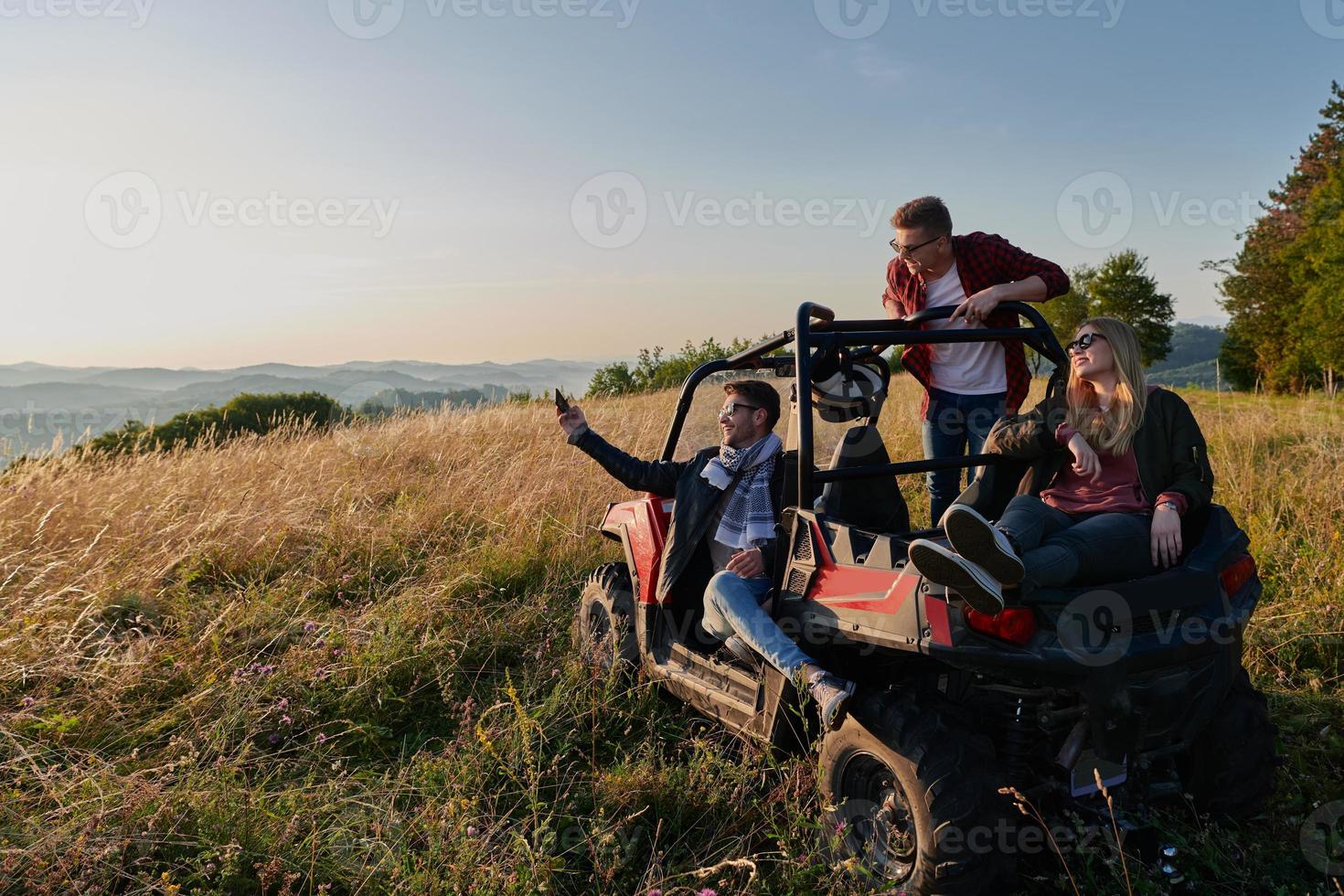 group young happy people enjoying beautiful sunny day while driving a off road buggy car photo