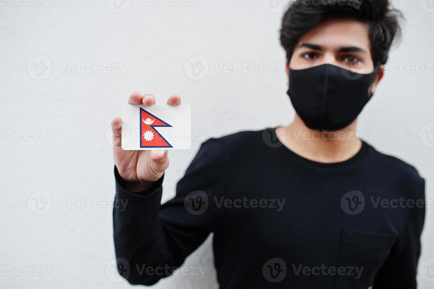 Asian man wear all black with face mask hold Nepal flag in hand isolated on white background. Coronavirus country concept. photo