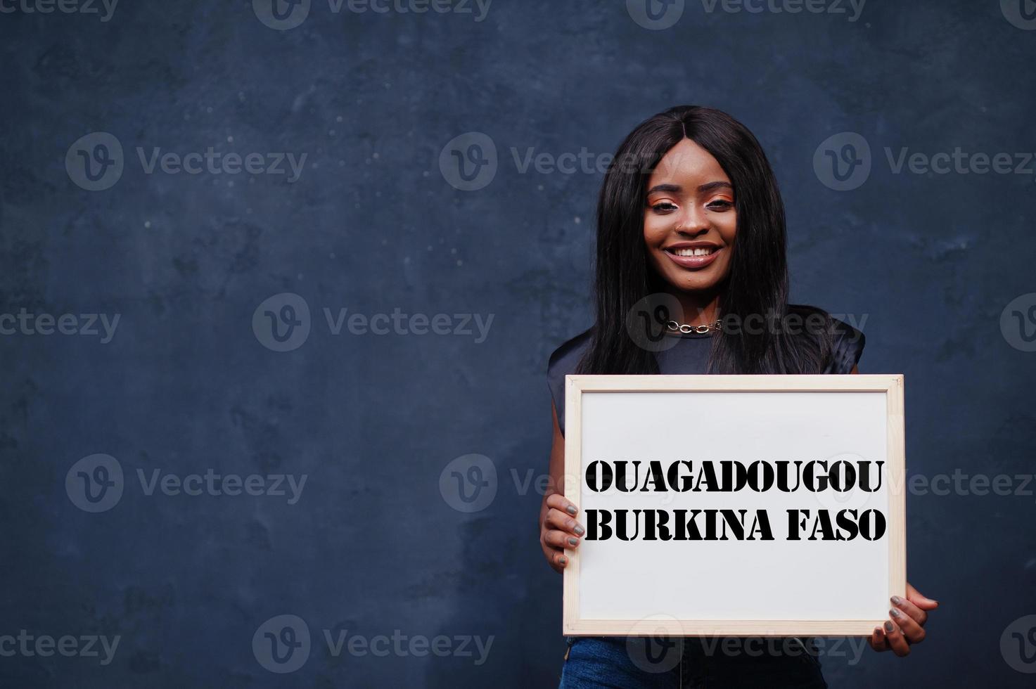 African woman hold white board with Ouagadougou Burkina Faso inscription. Most populous city in Africa concept. photo