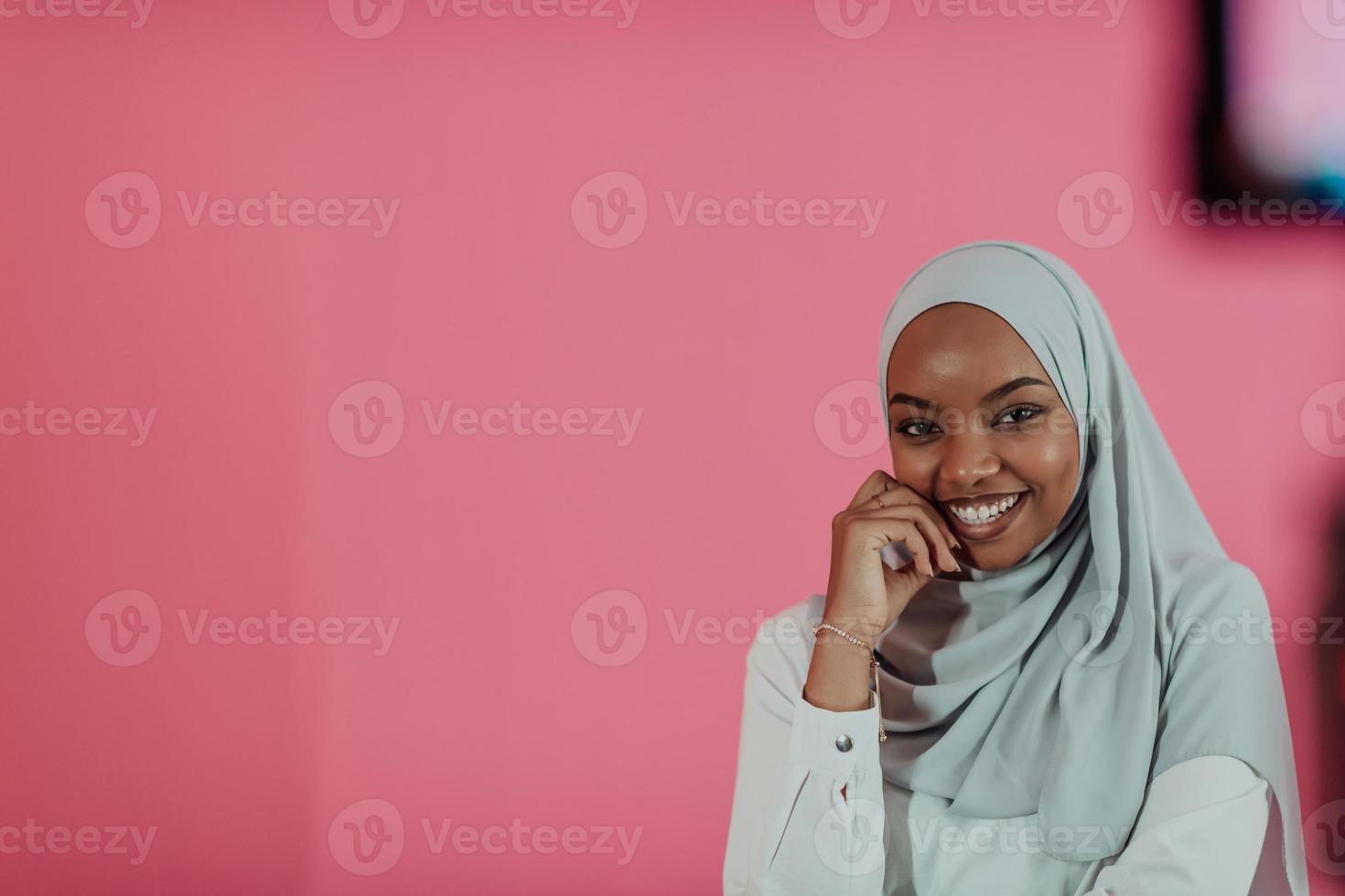 retrato de una joven belleza afro musulmana moderna con ropa islámica tradicional sobre fondo rosa plástico. enfoque selectivo foto