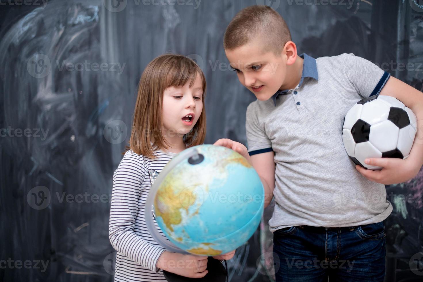 boy and little girl using globe of earth in front of chalkboard photo