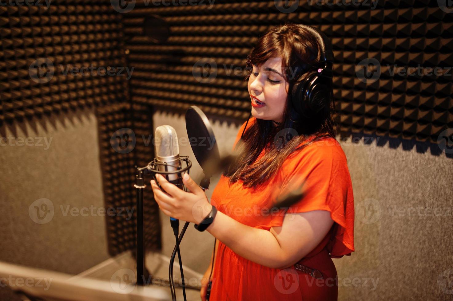 Young asian singer with microphone recording song in record music studio. photo