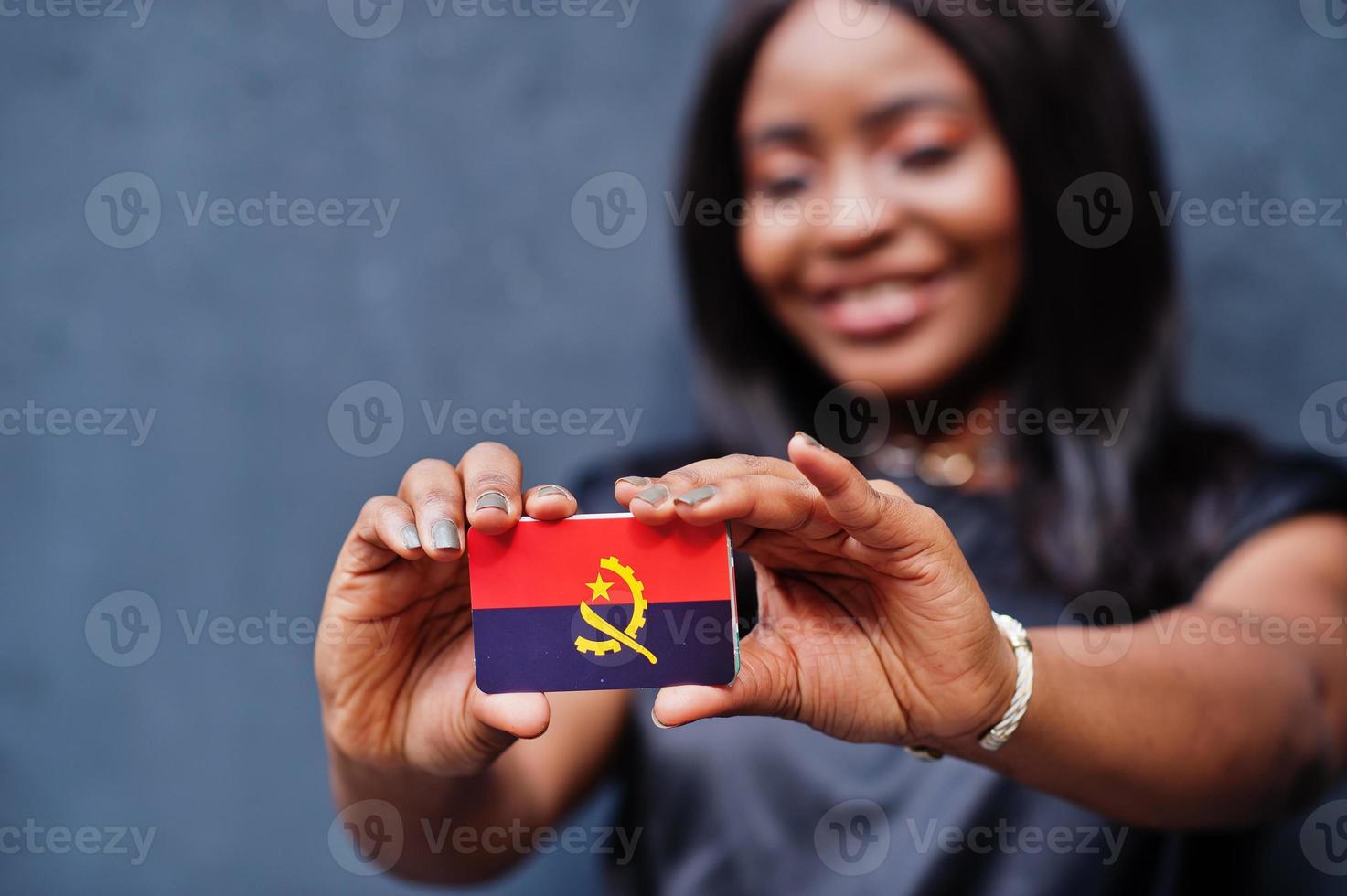 mujer africana sostiene una pequeña bandera de angola en las manos. foto