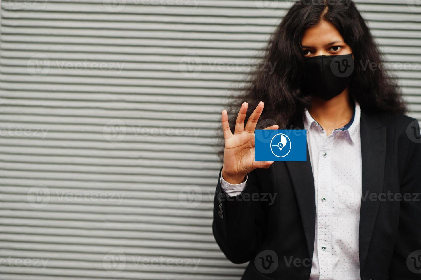Asian woman at formal wear and black protect face mask hold Yap flag at hand against gray background. Coronavirus at country concept. photo