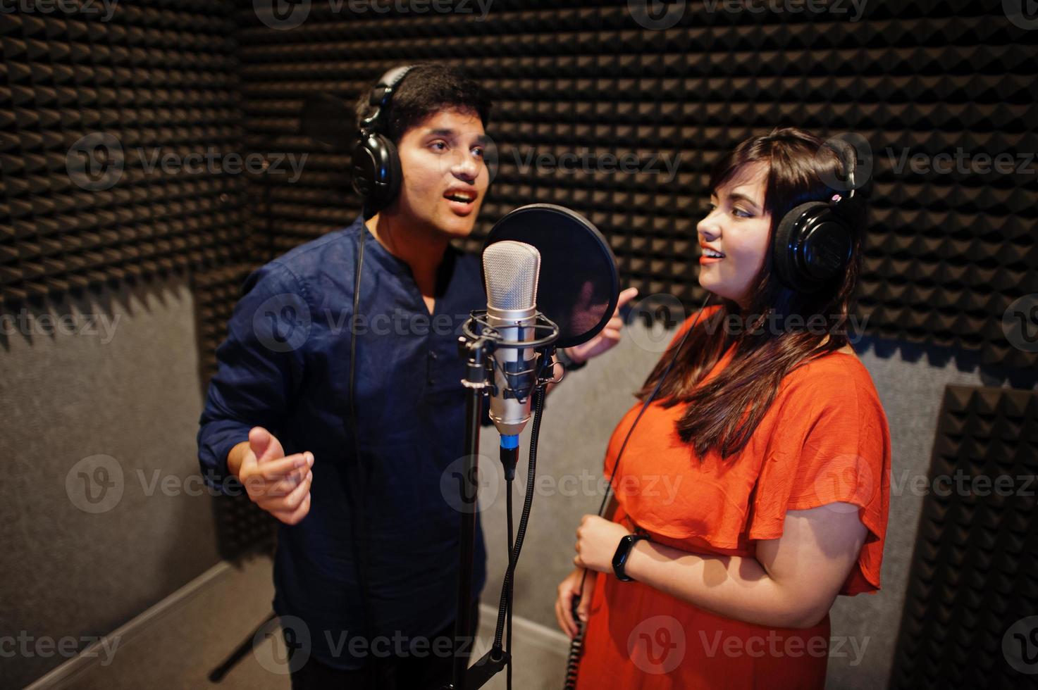 Young asian duet singers with microphone recording song in record music studio. photo