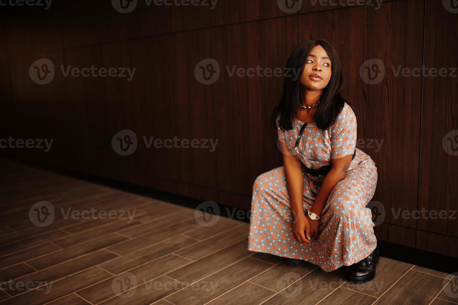 Fashion portrait of african american woman in long dress, boots indoor. photo