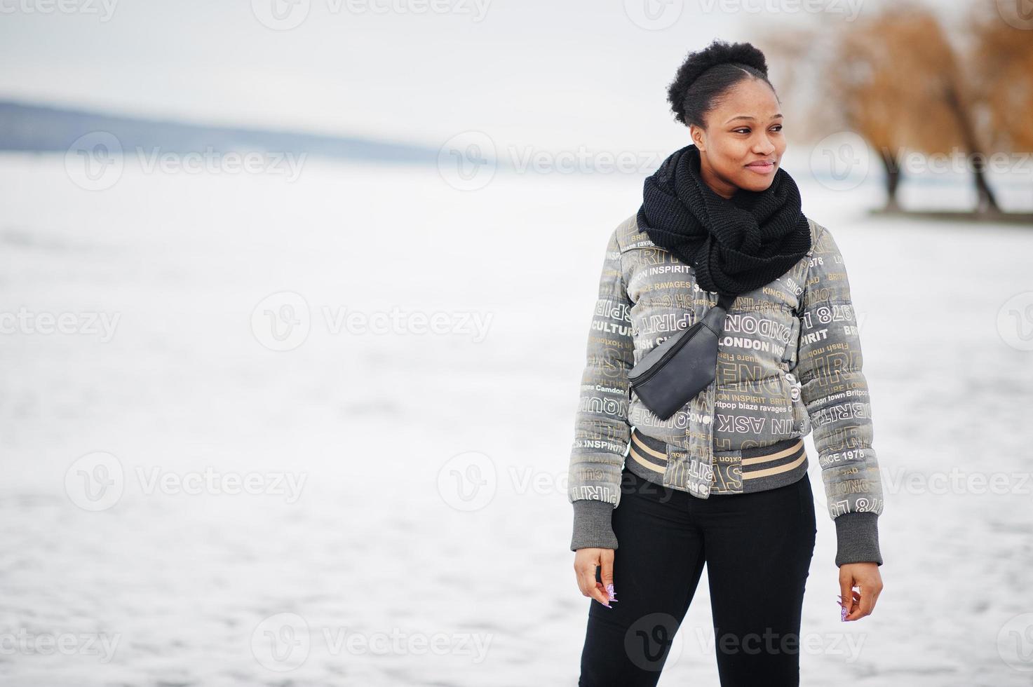 African woman wear in black scarf pose in frozen ice lake, winter day at Europe. photo