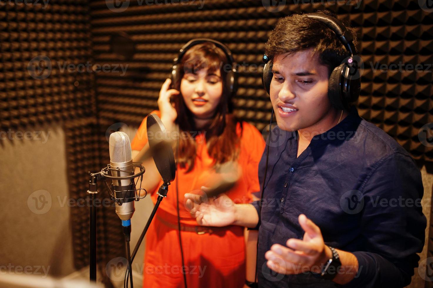 Young asian duet singers with microphone recording song in record music studio. photo
