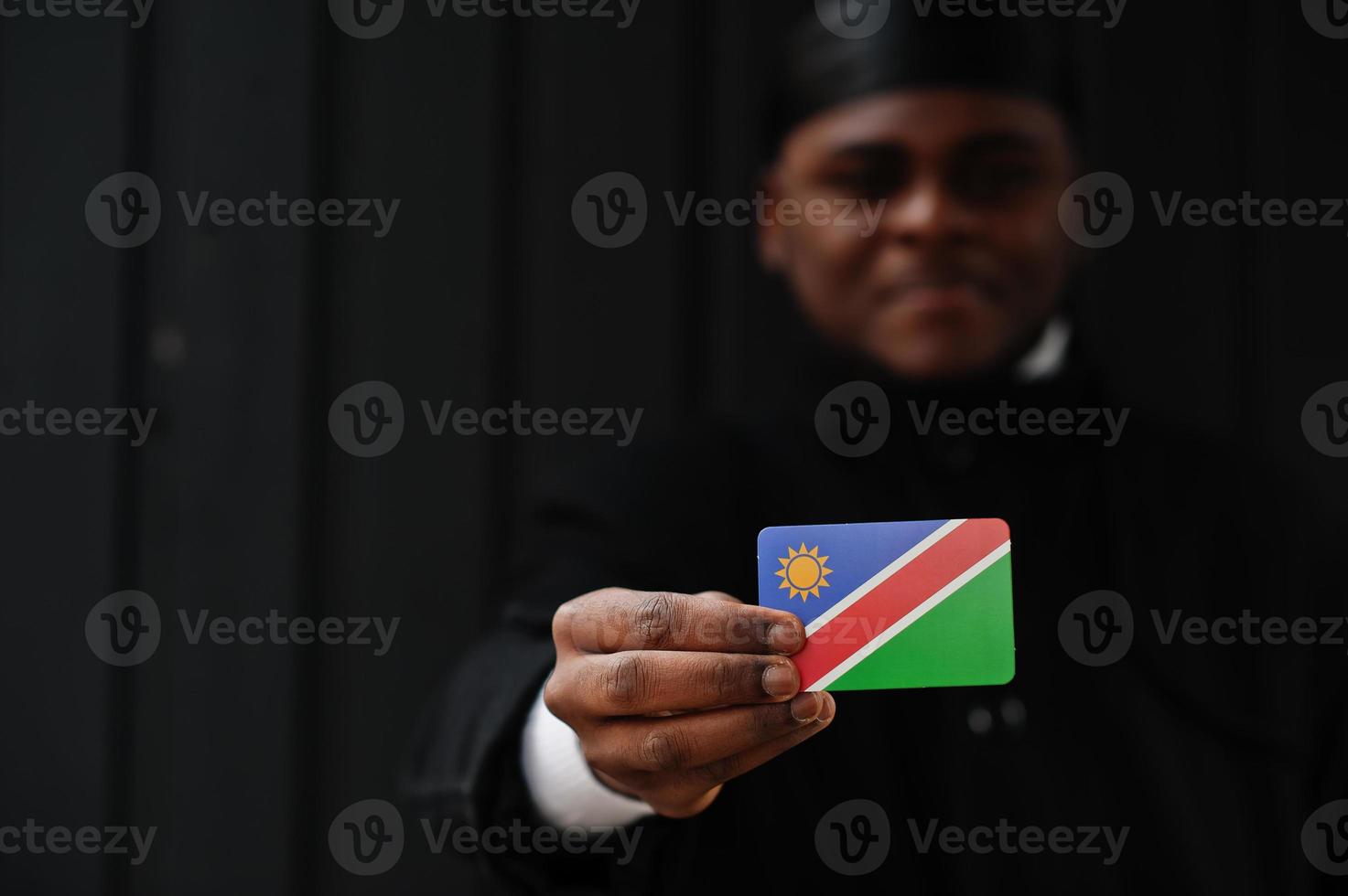 el hombre africano usa durag negro sostiene la bandera de namibia a mano aislado fondo oscuro. foto