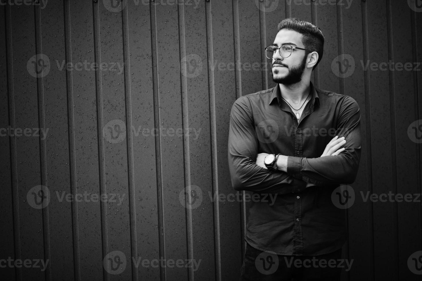 Middle eastern entrepreneur wear blue shirt, eyeglasses, against steel wall. photo