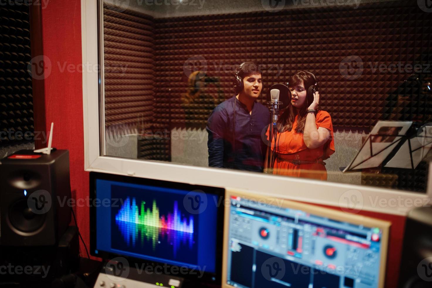 jóvenes cantantes de dúo asiáticos con micrófono grabando una canción en un estudio de grabación de música. foto