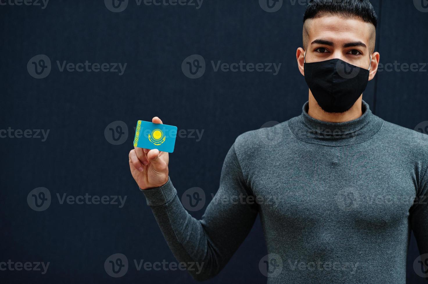Middle eastern man in gray turtleneck and black face protect mask show Kazakhstan flag isolated background. photo