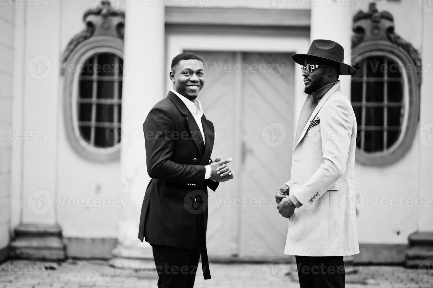 dos hombres negros de moda. retrato de moda de modelos masculinos afroamericanos. llevar traje, abrigo y sombrero. foto