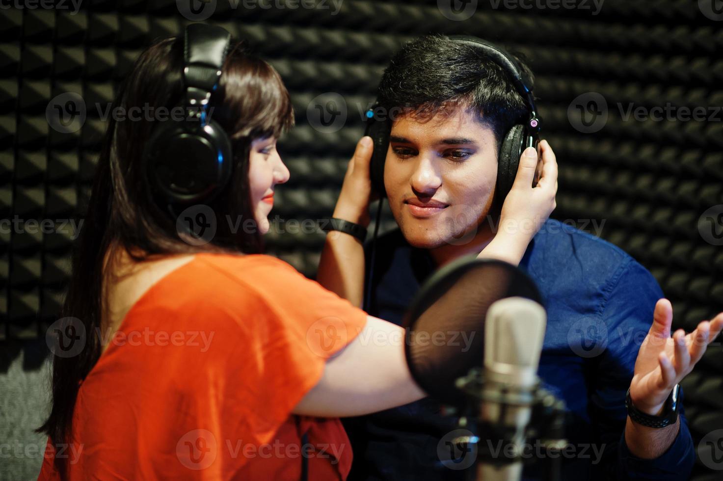 jóvenes cantantes de dúo asiáticos con micrófono grabando una canción en un estudio de grabación de música. foto