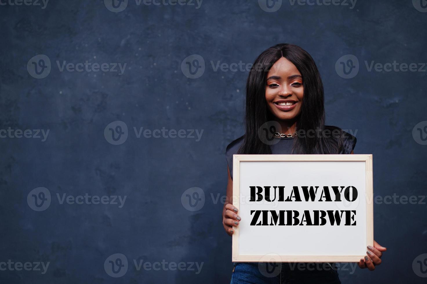 African woman hold white board with Bulawayo Zimbabwe inscription. Most populous city in Africa concept. photo