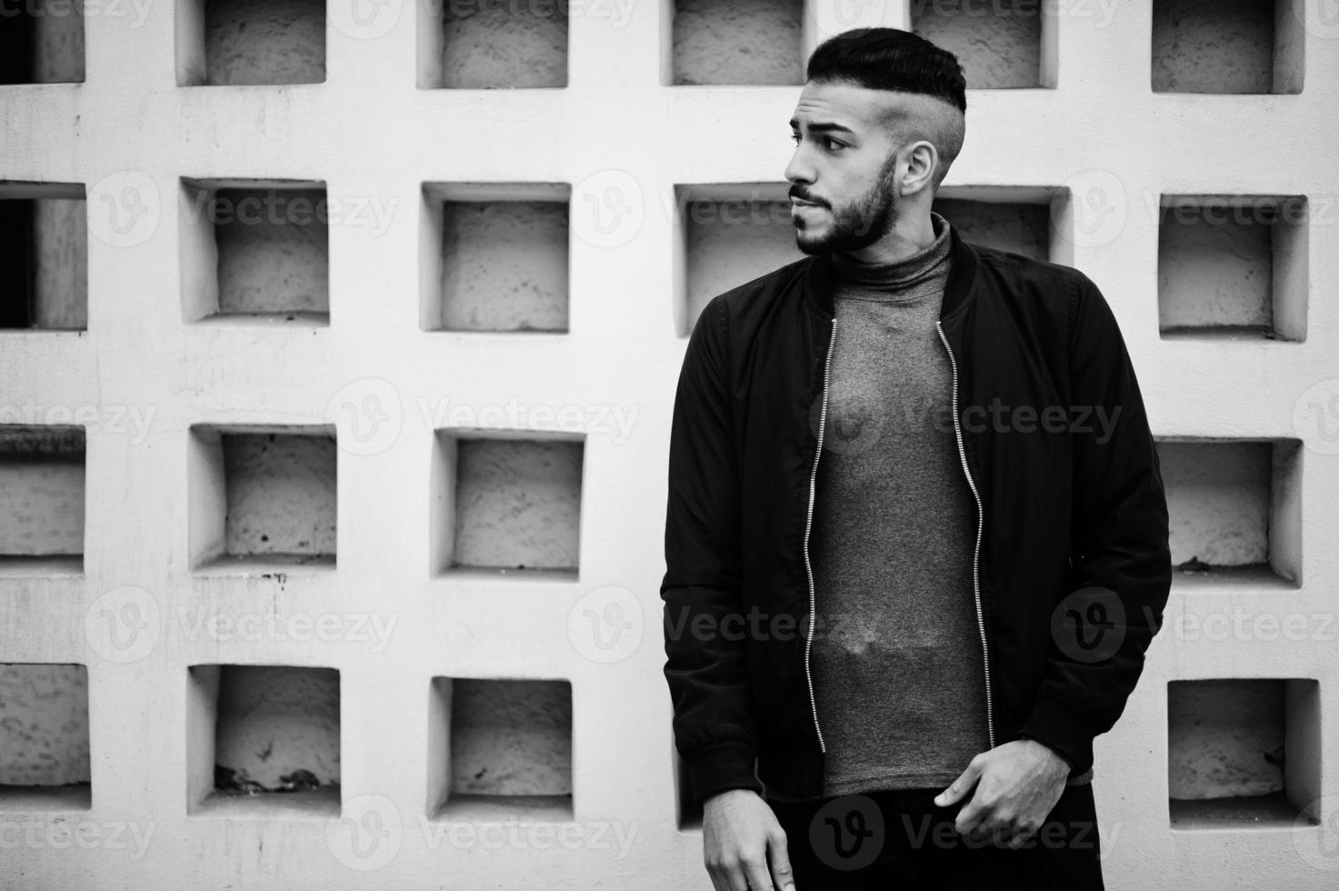 retrato de un elegante hombre de barba árabe con cuello alto gris y jaket negro. chico modelo árabe. foto