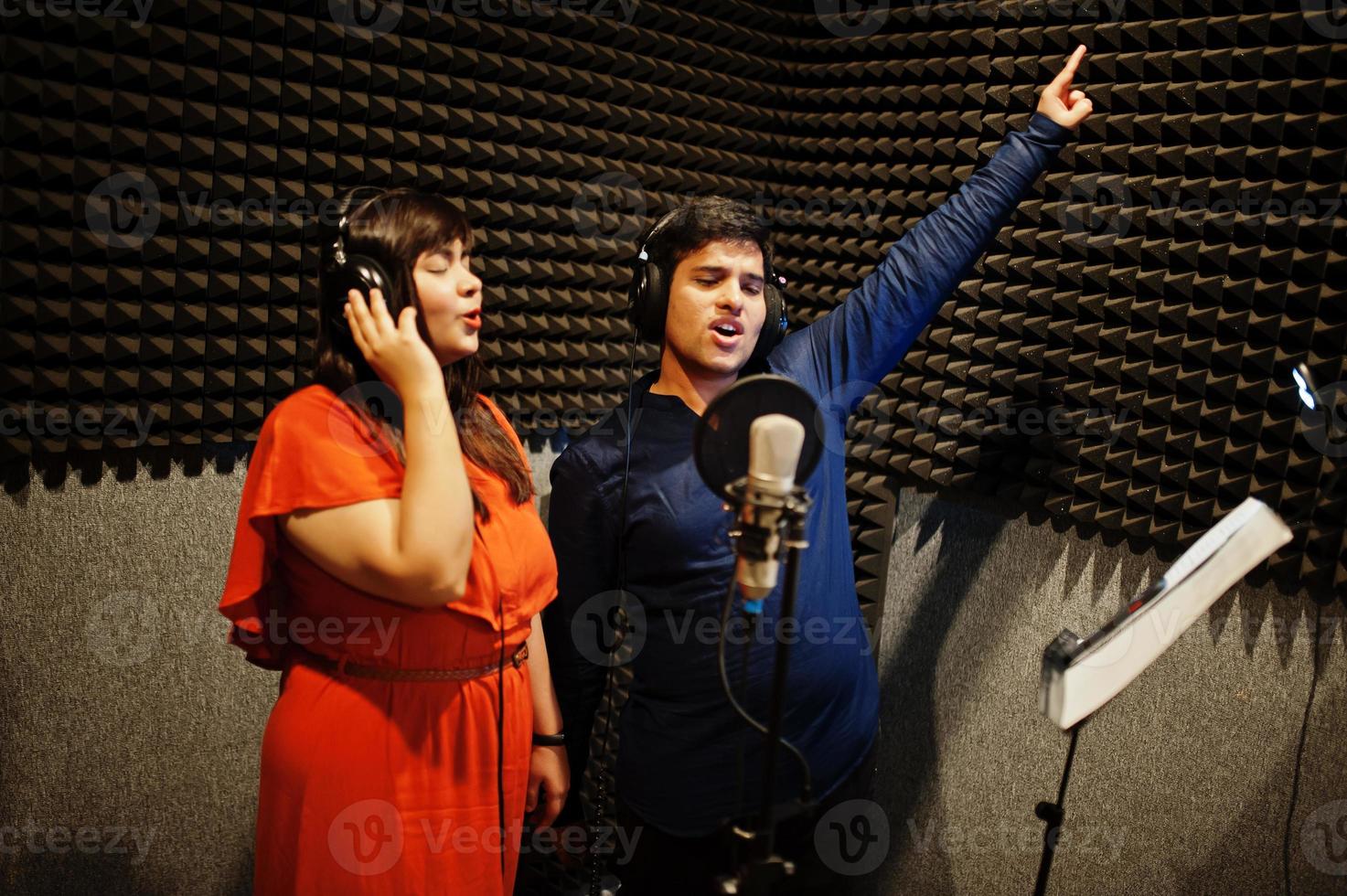 Young asian duet singers with microphone recording song in record music studio. photo