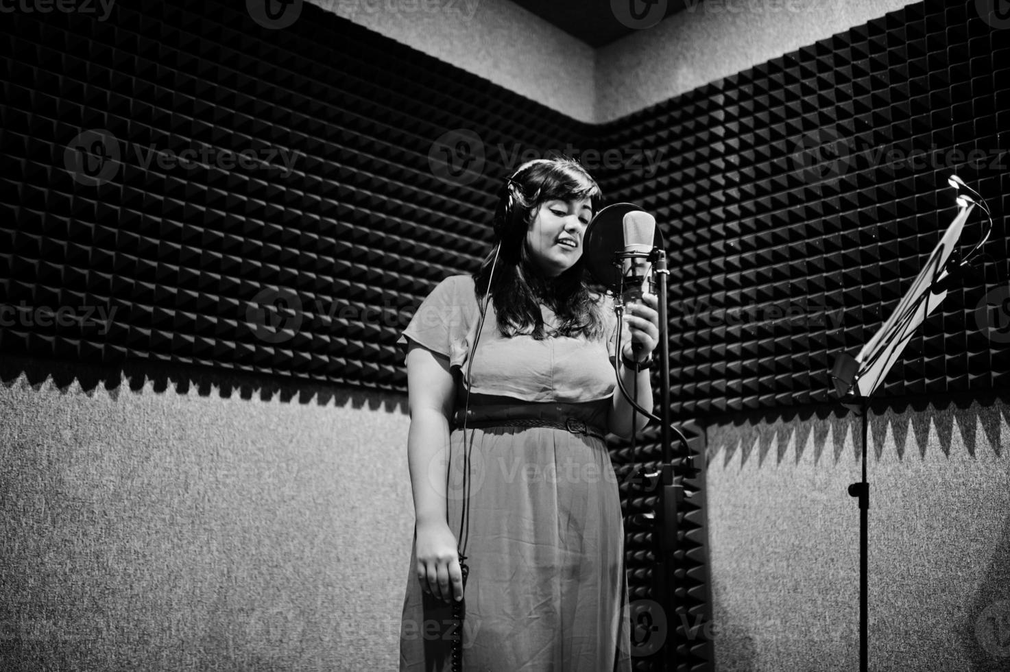 joven cantante asiático con micrófono grabando una canción en un estudio de grabación de música. foto