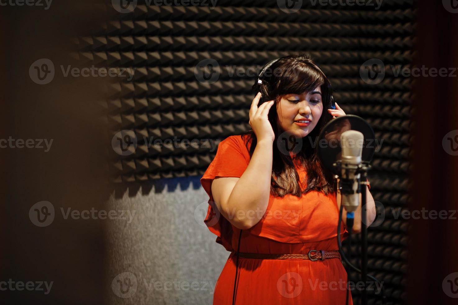 Young asian singer with microphone recording song in record music studio. photo