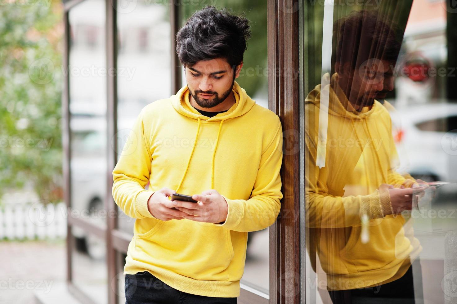 hombre indio joven hipster urbano en una sudadera amarilla de moda