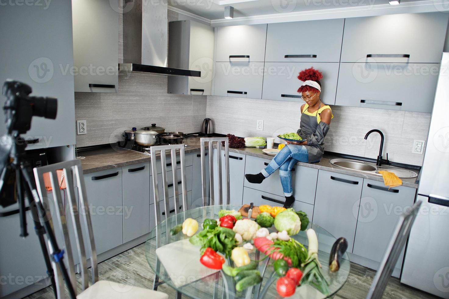 African american woman filming her blog broadcast about healthy food at home kitchen.  She hold plate with salad. photo