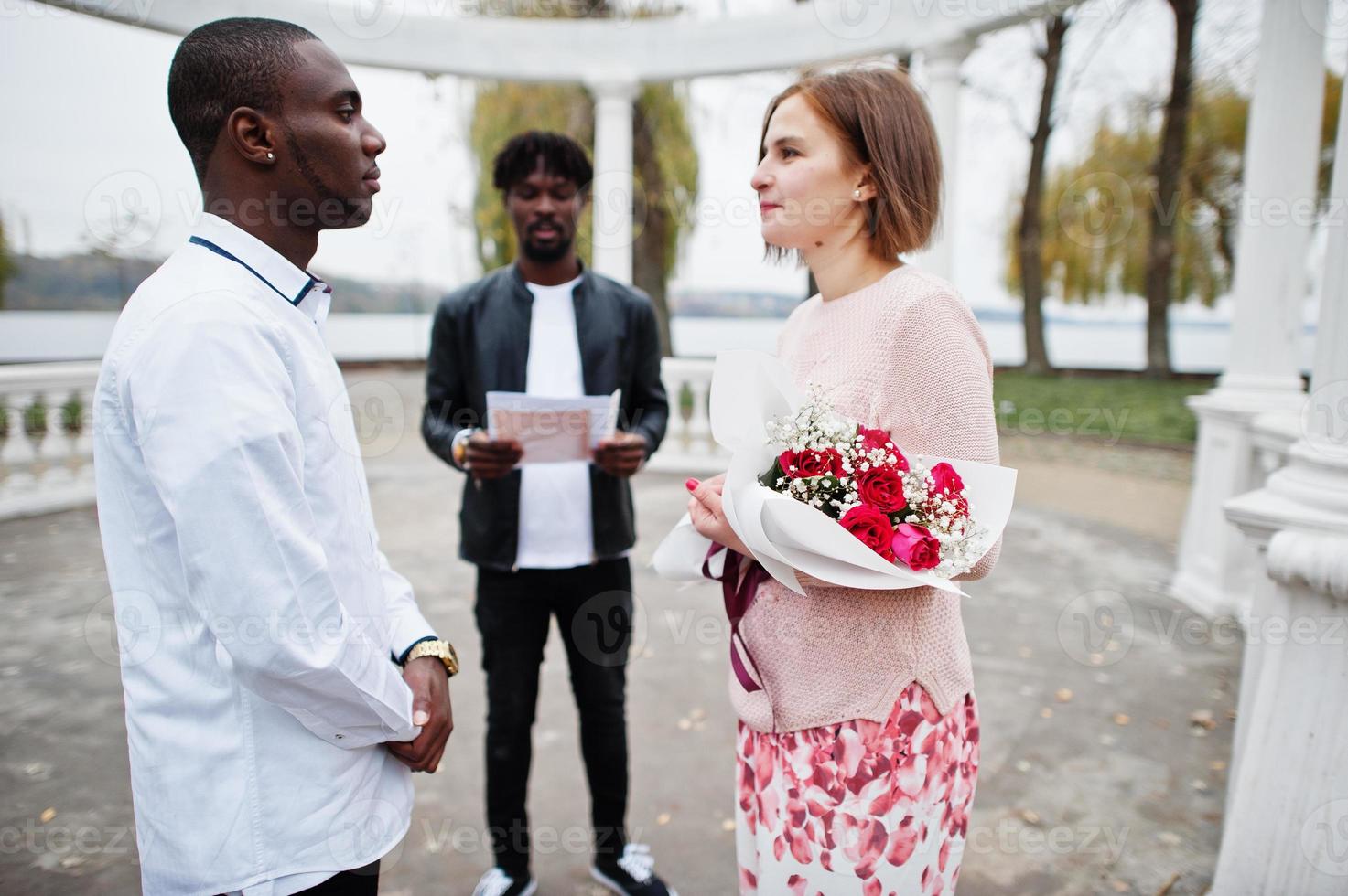 Wedding engagement ceremony with pastor. Happy multiethnic couple in love story. Relationships of african man and white european woman. photo