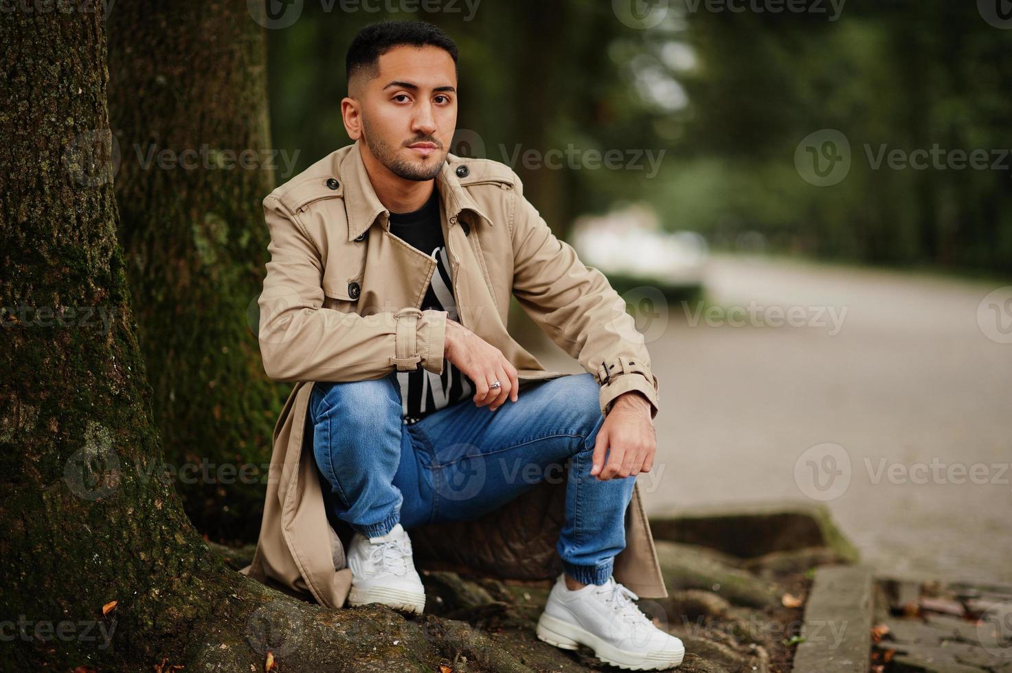 hombre kuwaití con estilo en gabardina caminando en el parque. foto