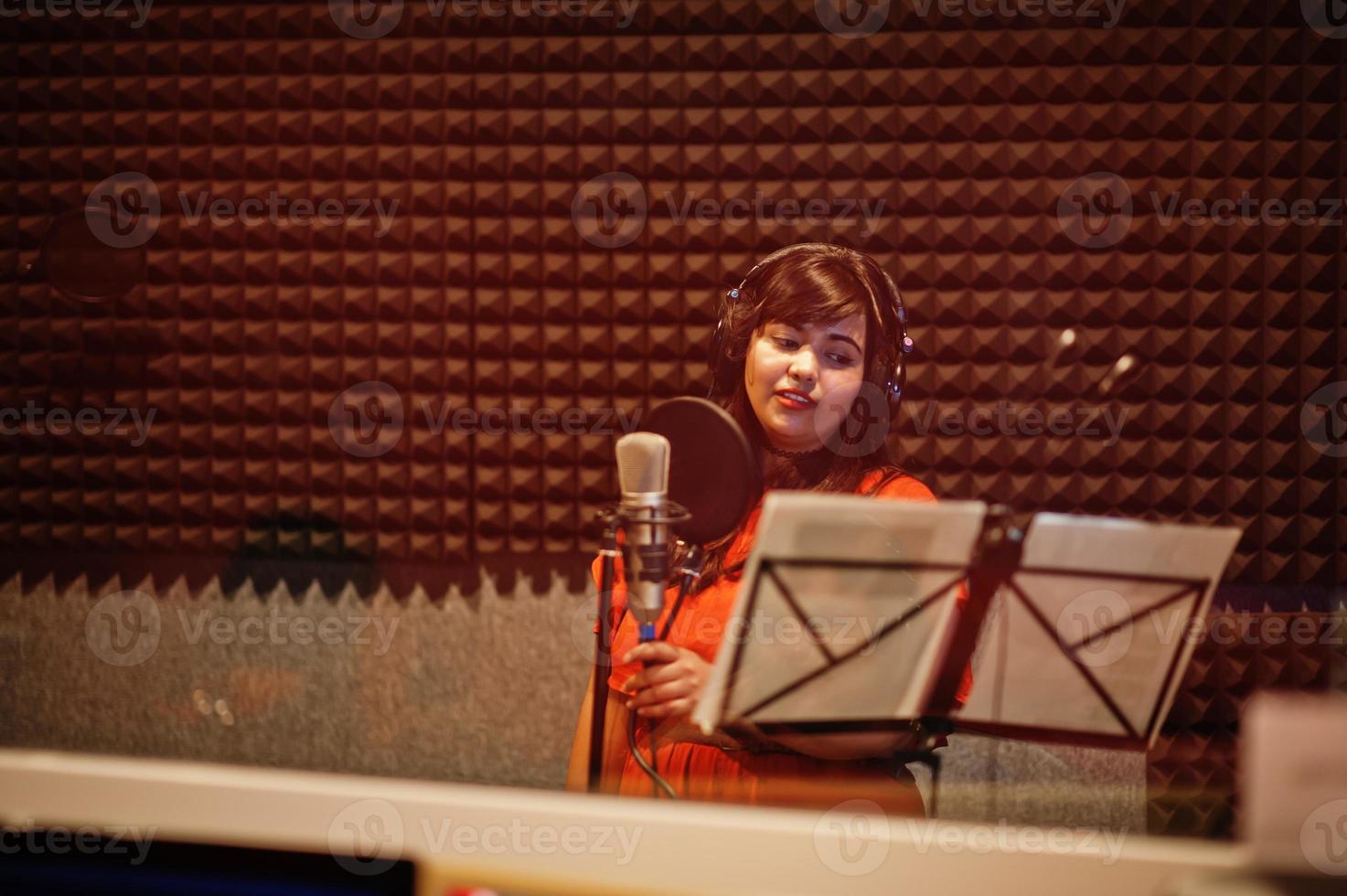 Young asian singer with microphone recording song in record music studio. photo