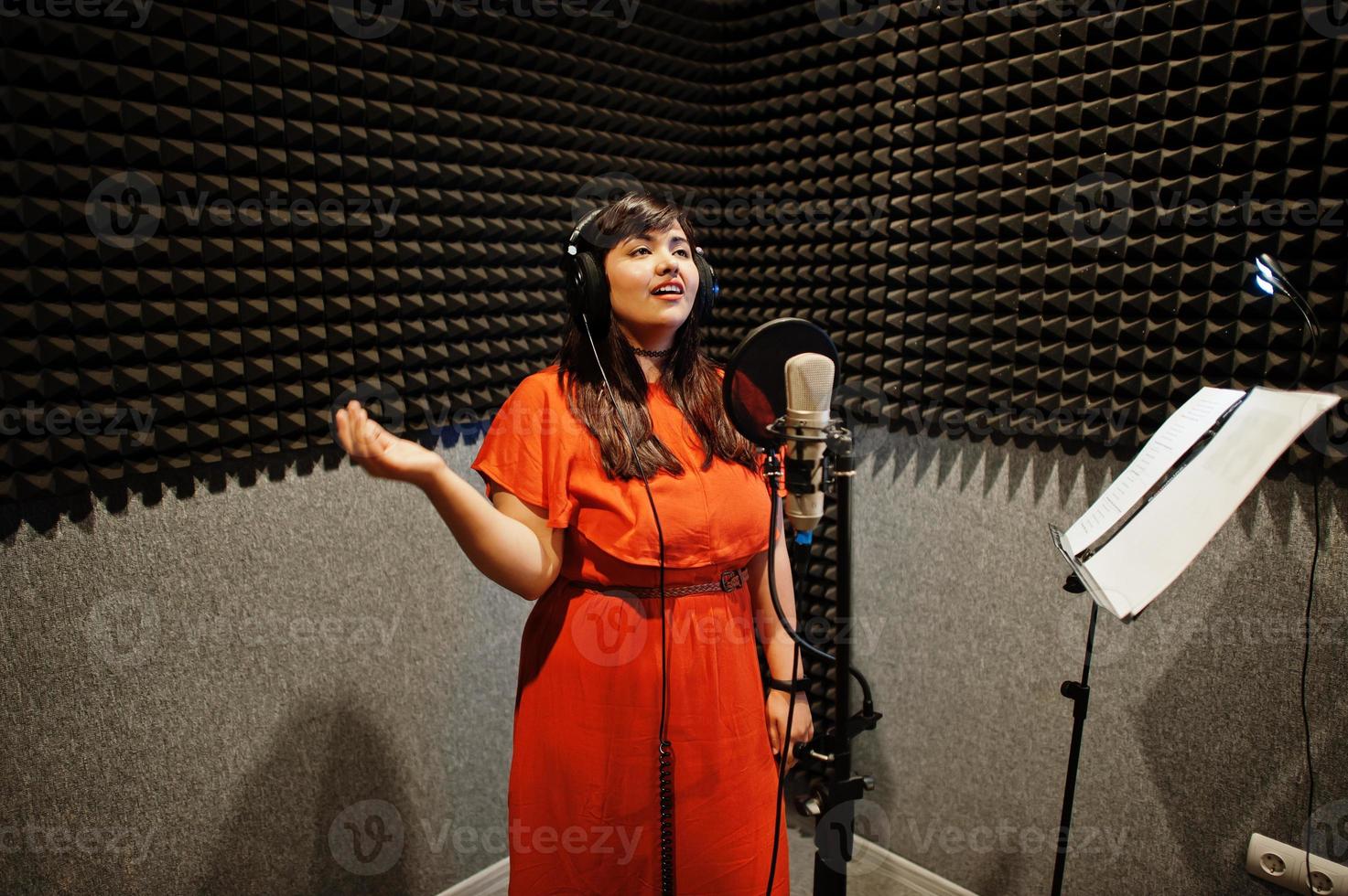 Young asian singer with microphone recording song in record music studio. photo