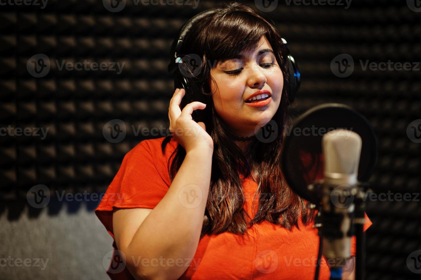 Young asian singer with microphone recording song in record music studio. photo