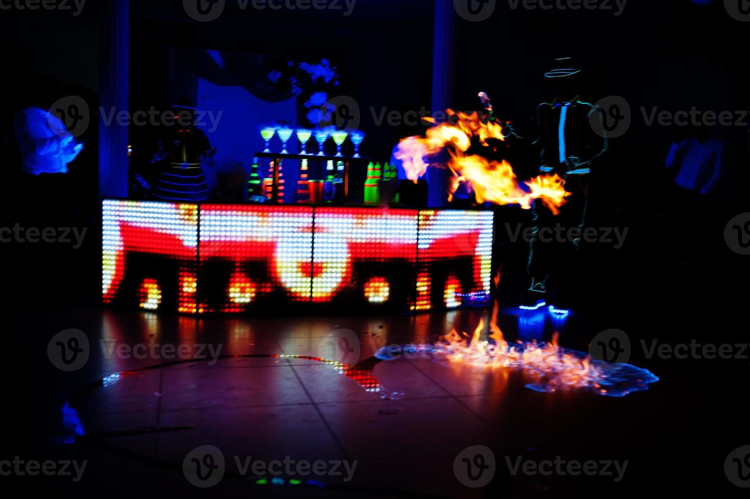 Professional barman and led light fire show. Silhouette of modern bartender shaking drink at night cocktail bar. photo