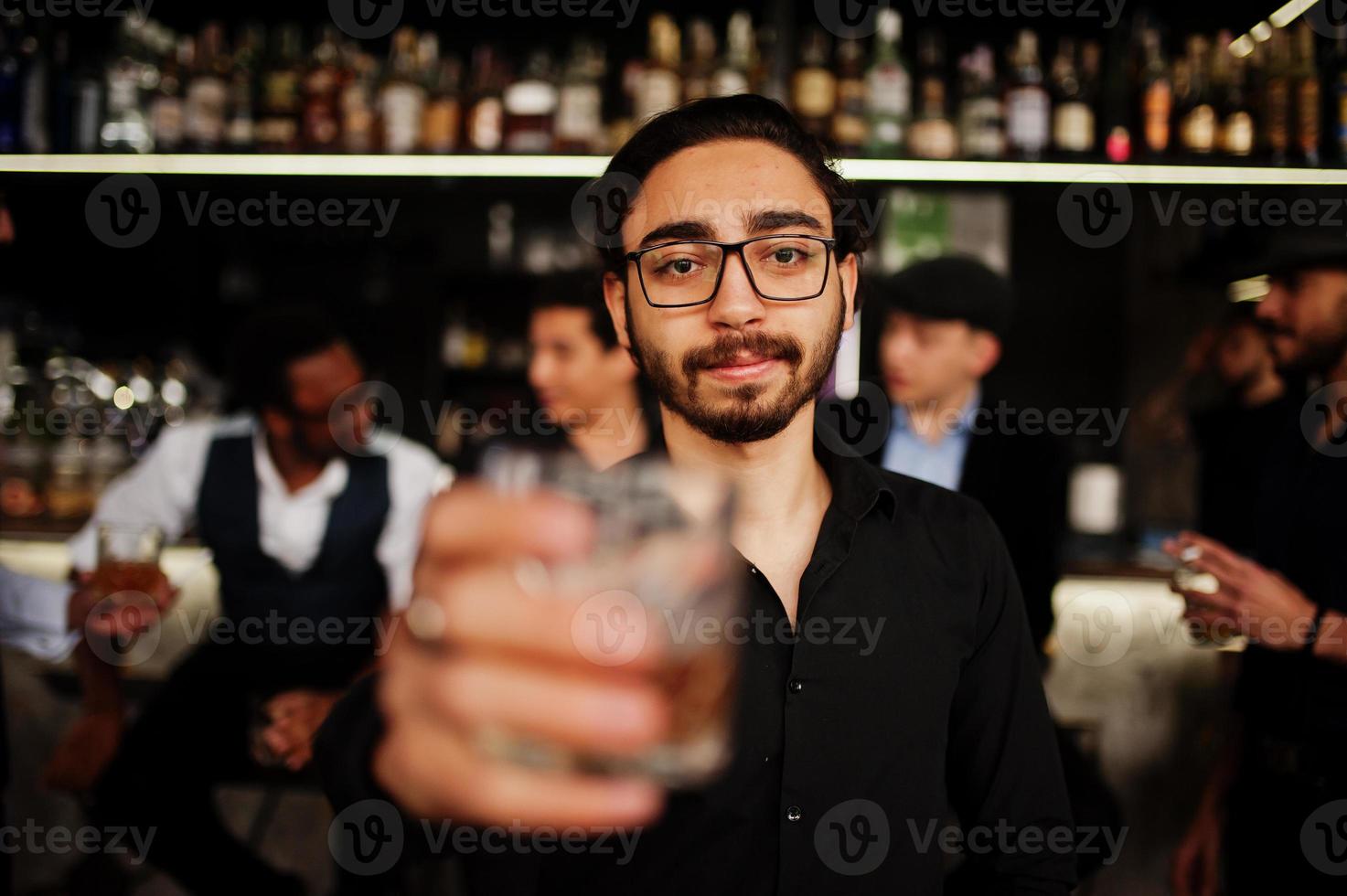 Stylish arab man against group of handsome retro well-dressed guys gangsters spend time at club, drinking on bar counter. Multiethnic male bachelor mafia party in restaurant. photo