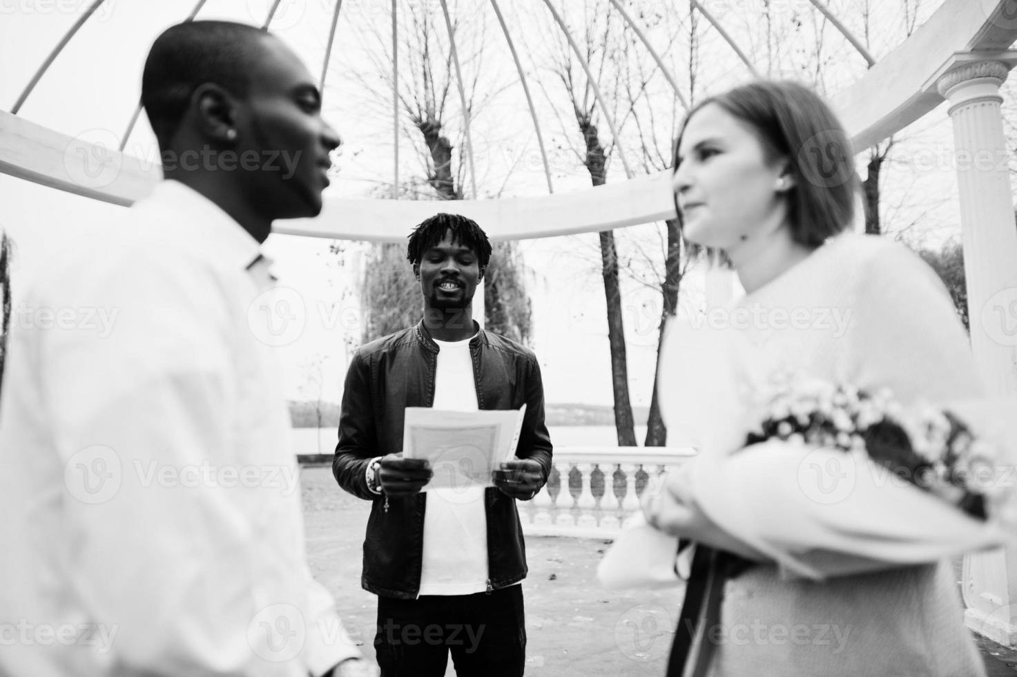 ceremonia de compromiso de boda con el pastor. feliz pareja multiétnica en la historia de amor. relaciones de hombre africano y mujer europea blanca. foto