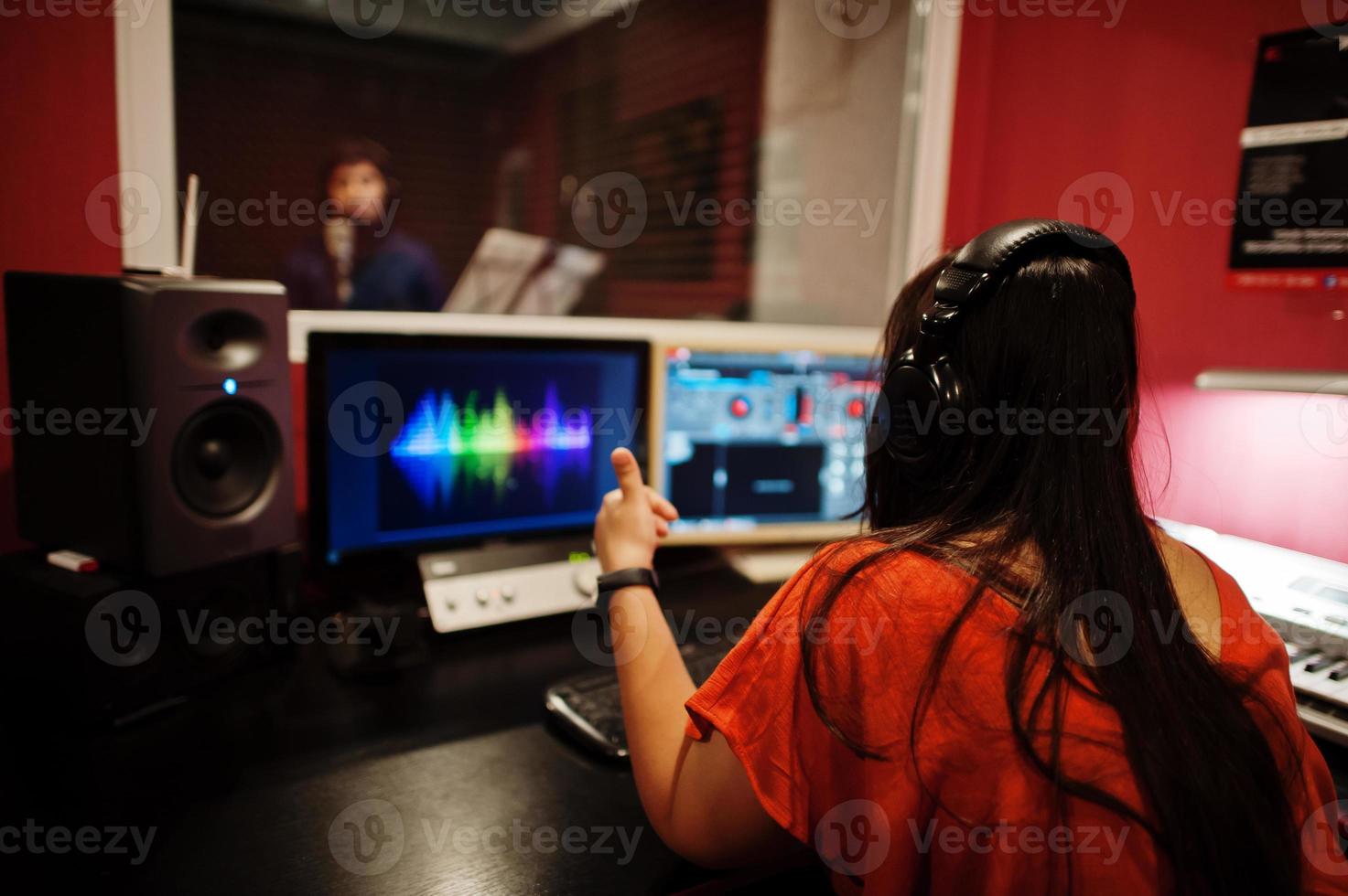 Young asian singer man with microphone recording song in record music studio with sound producer. photo