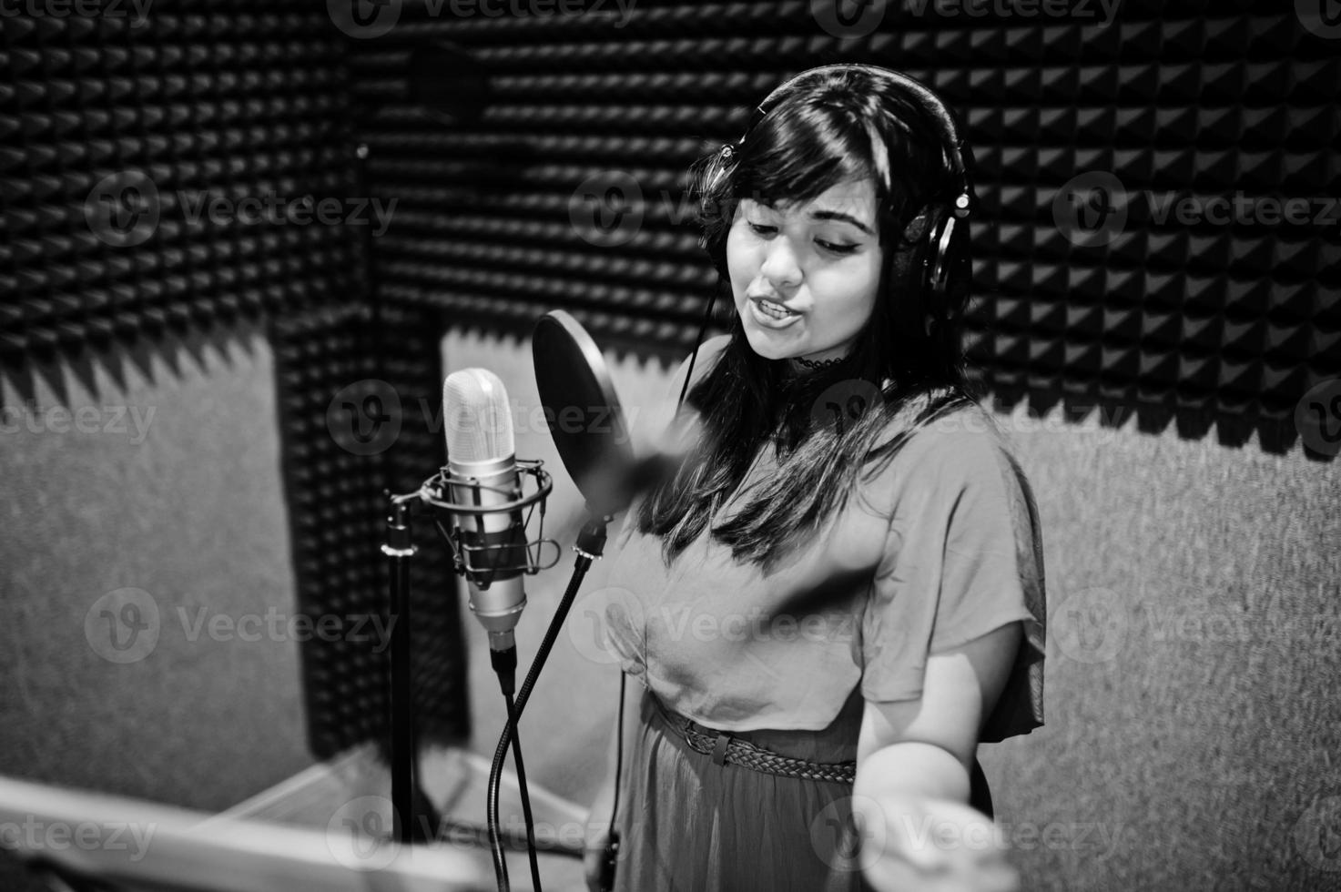 Young asian singer with microphone recording song in record music studio. photo