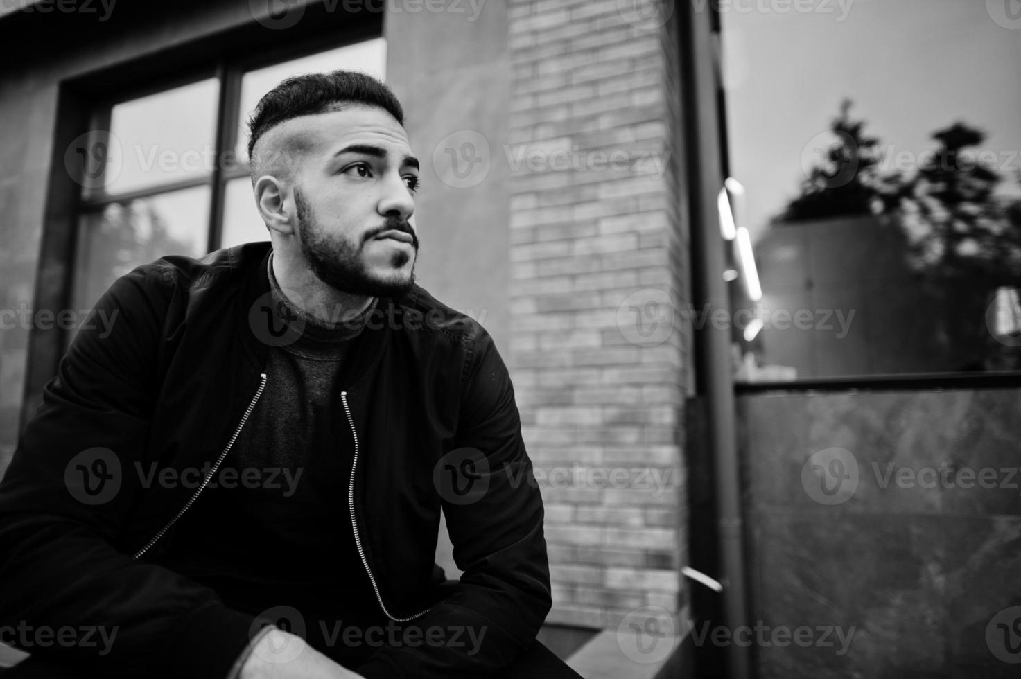 Portrait of stylish arab beard man wear grey turtleneck and black jaket. Arabian model guy squat. photo