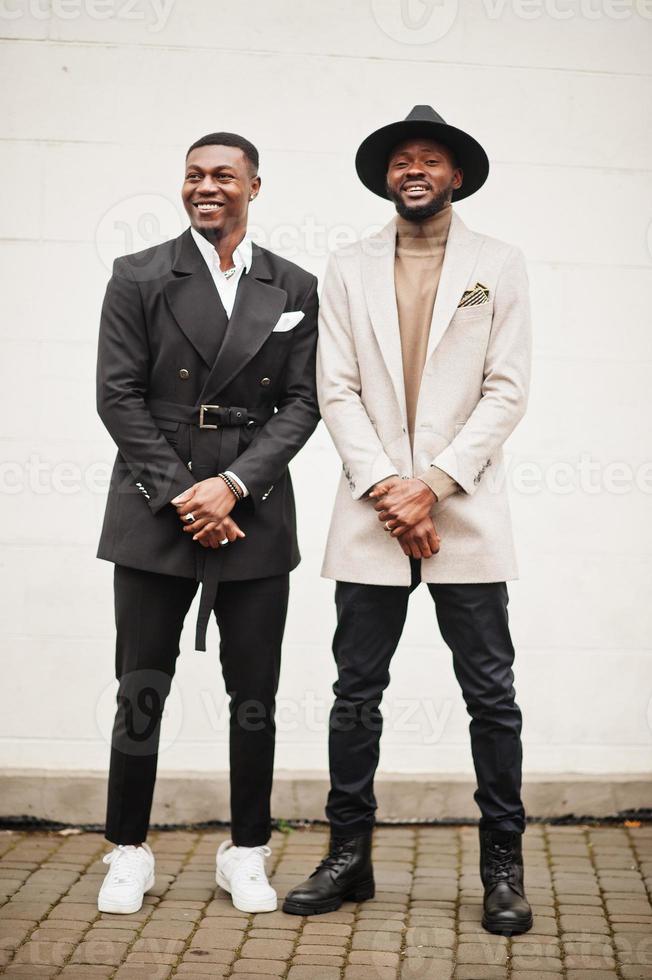 dos hombres negros de moda. retrato de moda de modelos masculinos afroamericanos. llevar traje, abrigo y sombrero. foto