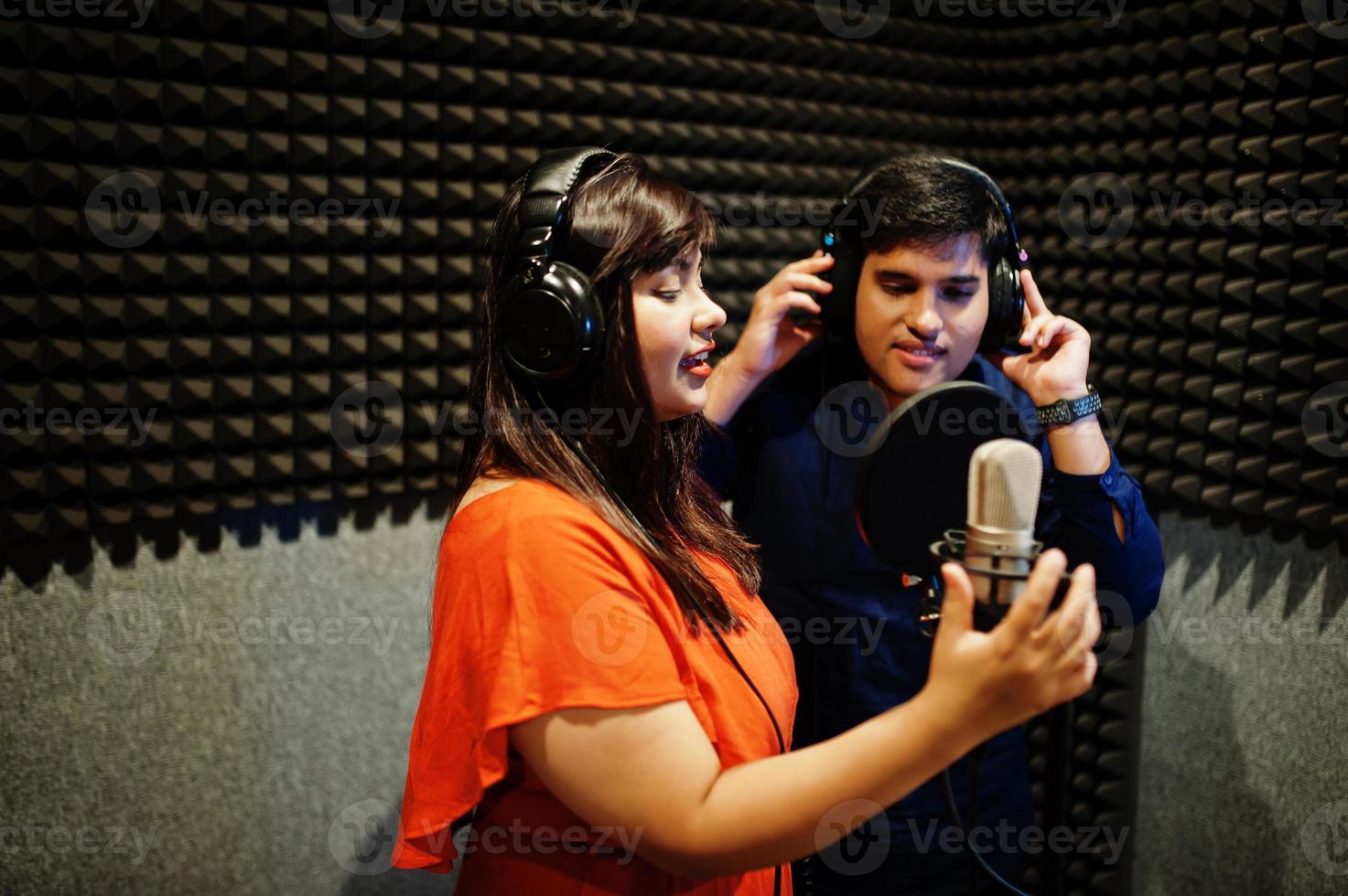 jóvenes cantantes de dúo asiáticos con micrófono grabando una canción en un estudio de grabación de música. foto