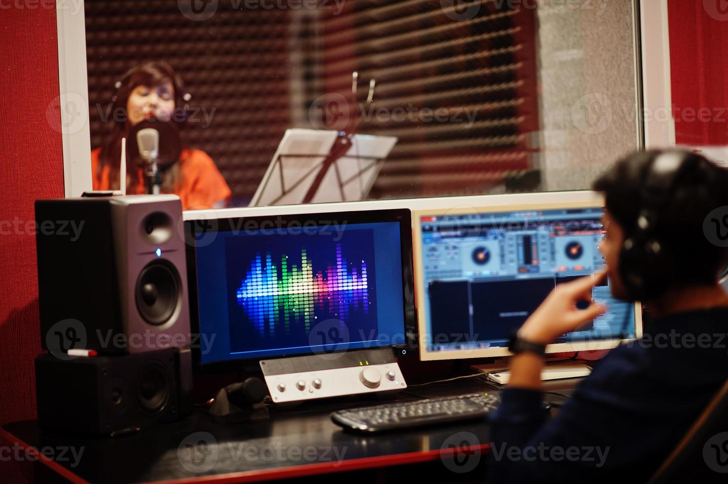 Young asian singer with microphone recording song in record music studio with sound producer. photo