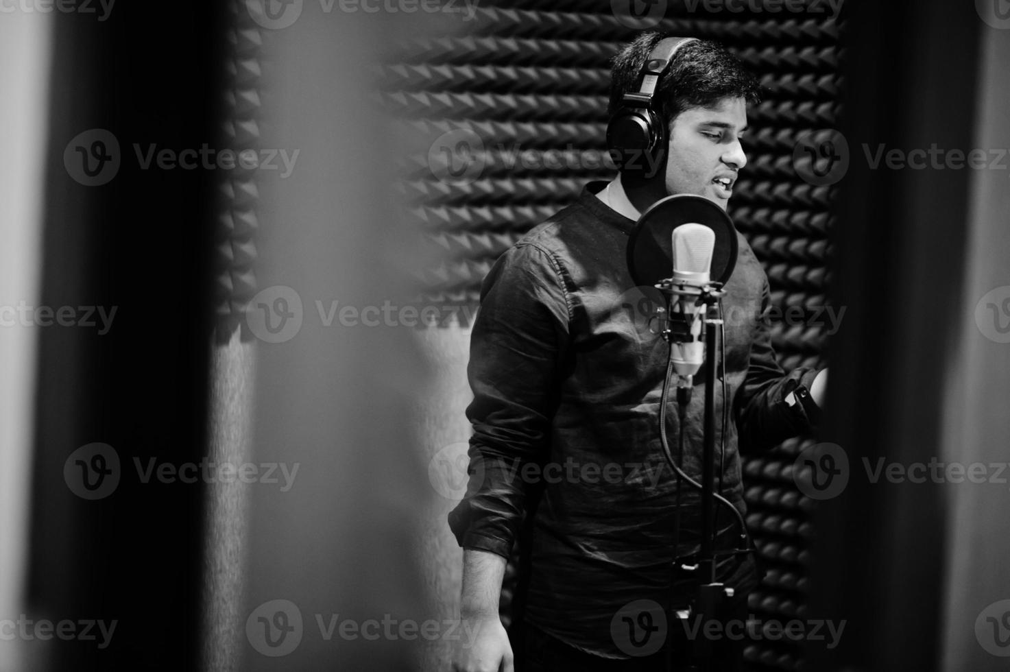 joven cantante asiático con micrófono grabando una canción en un estudio de grabación de música. foto