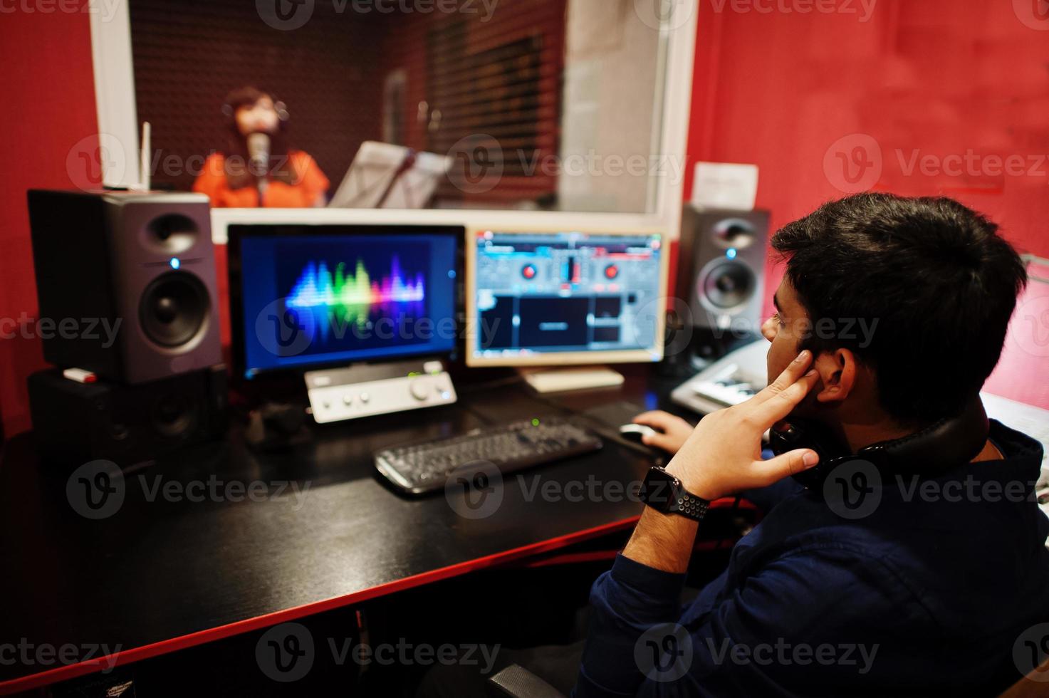 Young asian singer with microphone recording song in record music studio with sound producer. photo