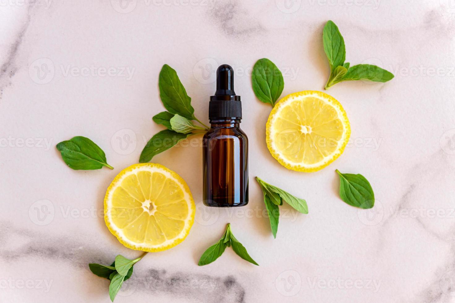 Vitamin C serum in cosmetic bottle with lemon citrus slices with green leaves on white background. Citrus essential oil, cosmetics aromatherapy. Organic SPA cosmetics with herbal ingredients. photo