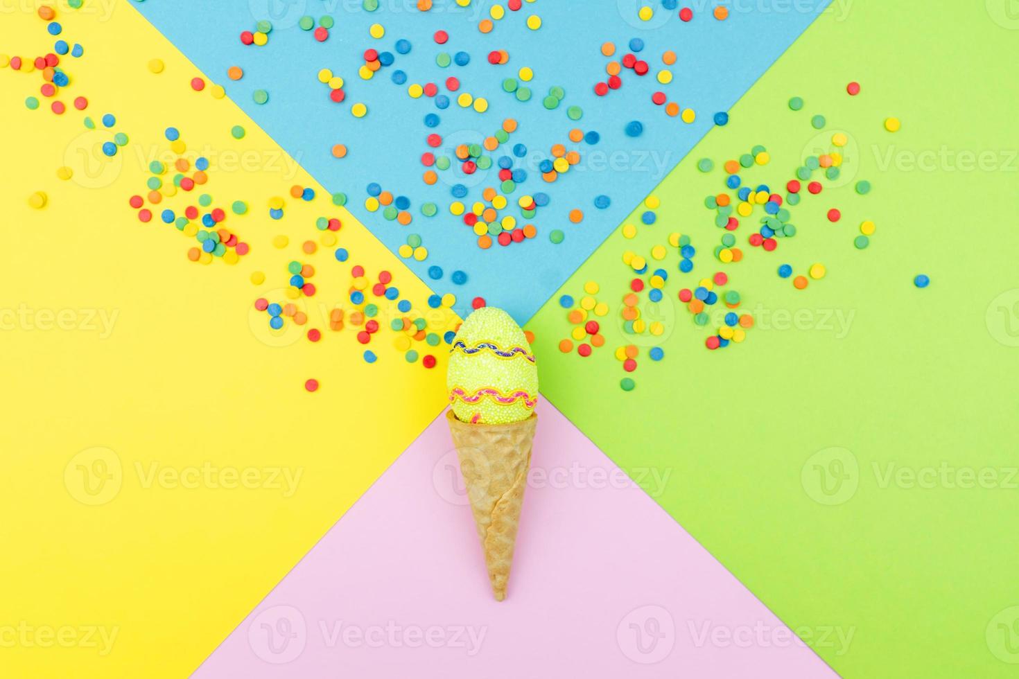 Pop colors. Festive multicolored background with bright sugar sprinkles scattered on paper, wafer cone end easter egg. photo