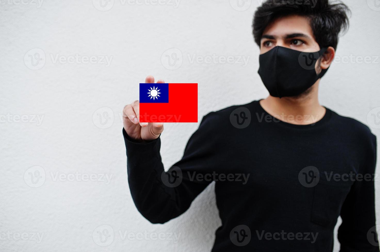 Asian man wear all black with face mask hold Taiwan flag in hand isolated on white background. Coronavirus country concept. photo