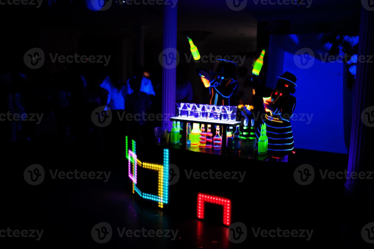 Professional barman and led light show. Silhouette of modern bartender shaking drink at night cocktail bar. photo