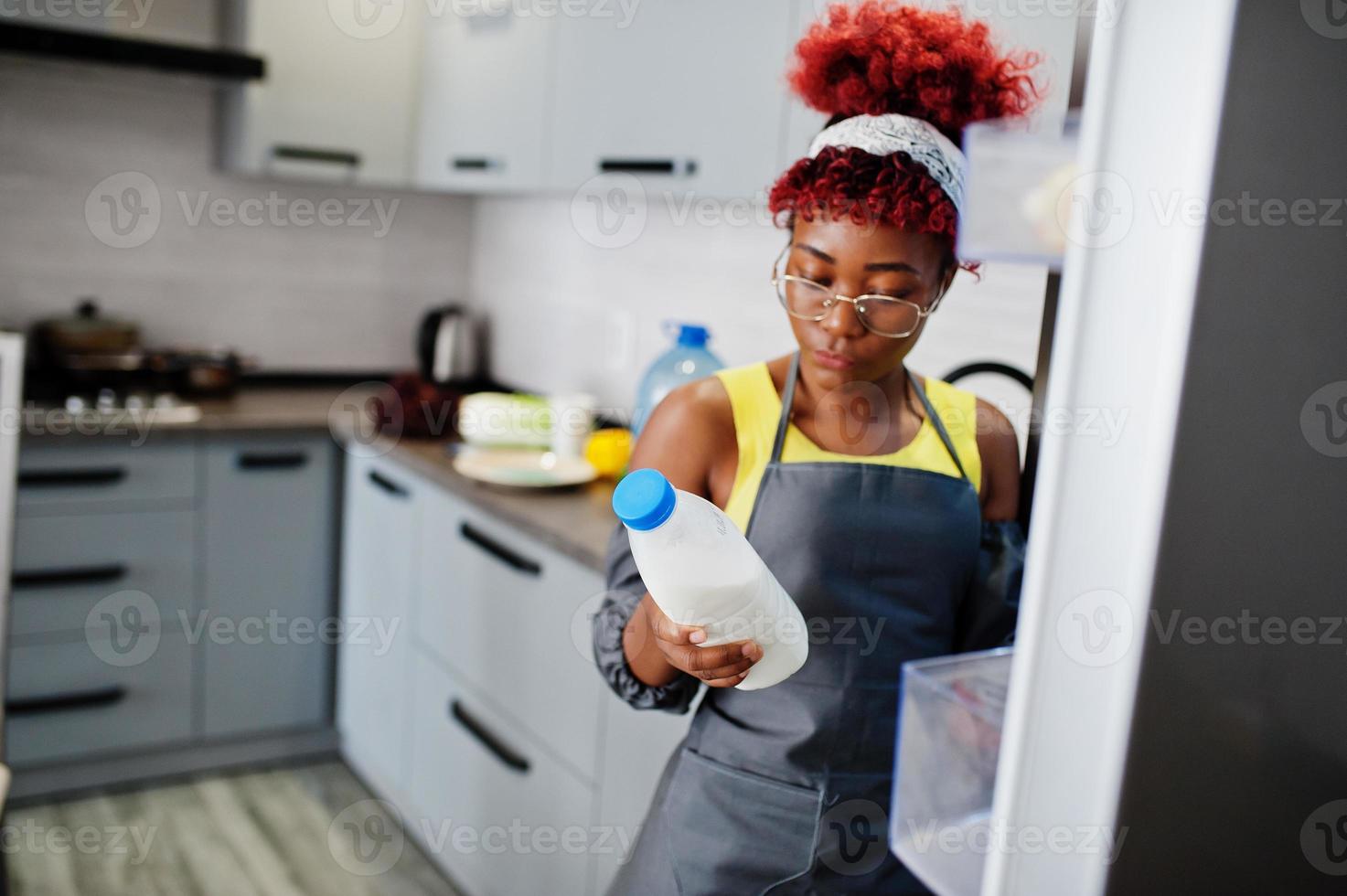 African american woman at home kitchen open fridge and got milk bottle. photo