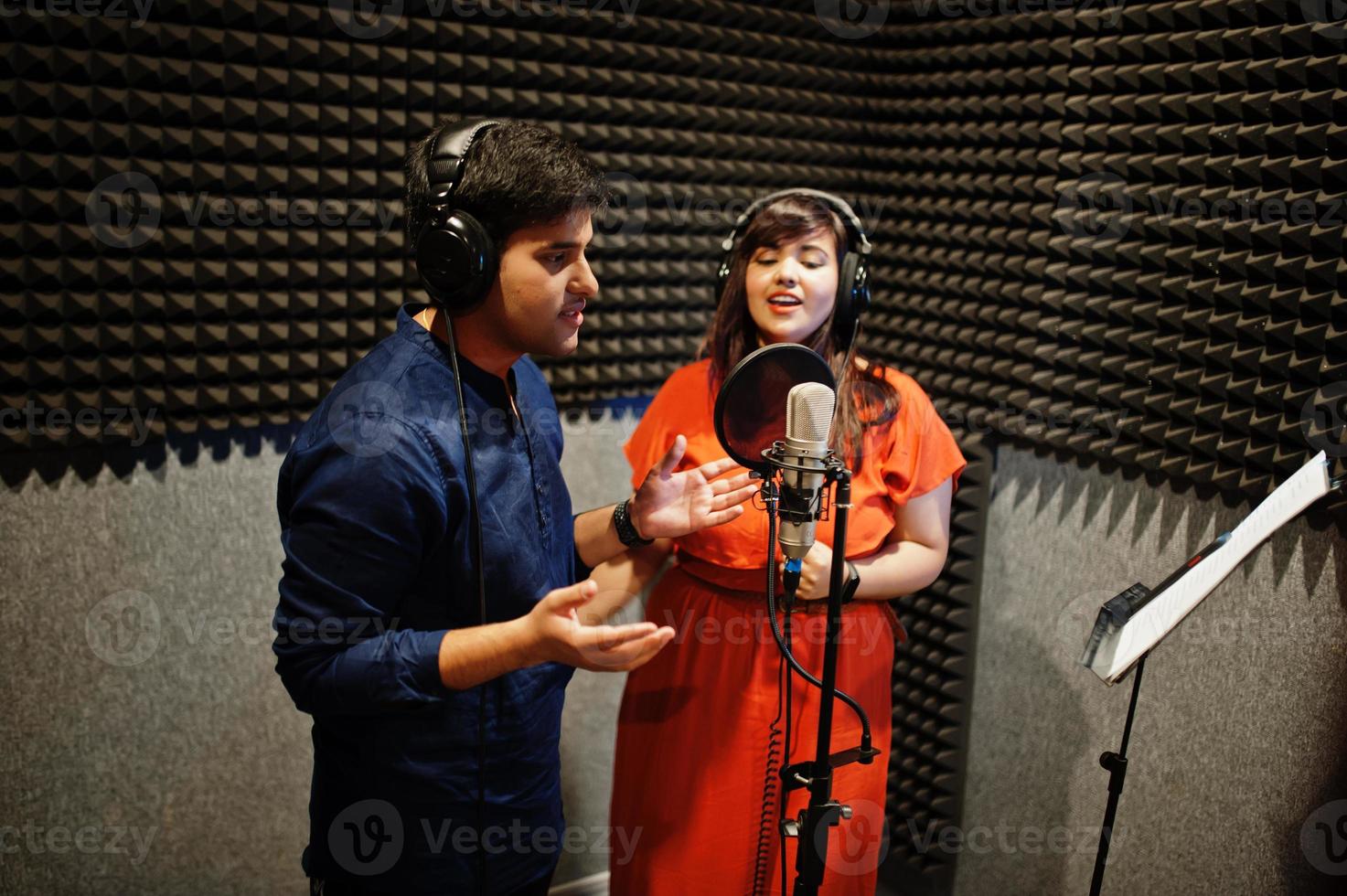 Young asian duet singers with microphone recording song in record music studio. photo