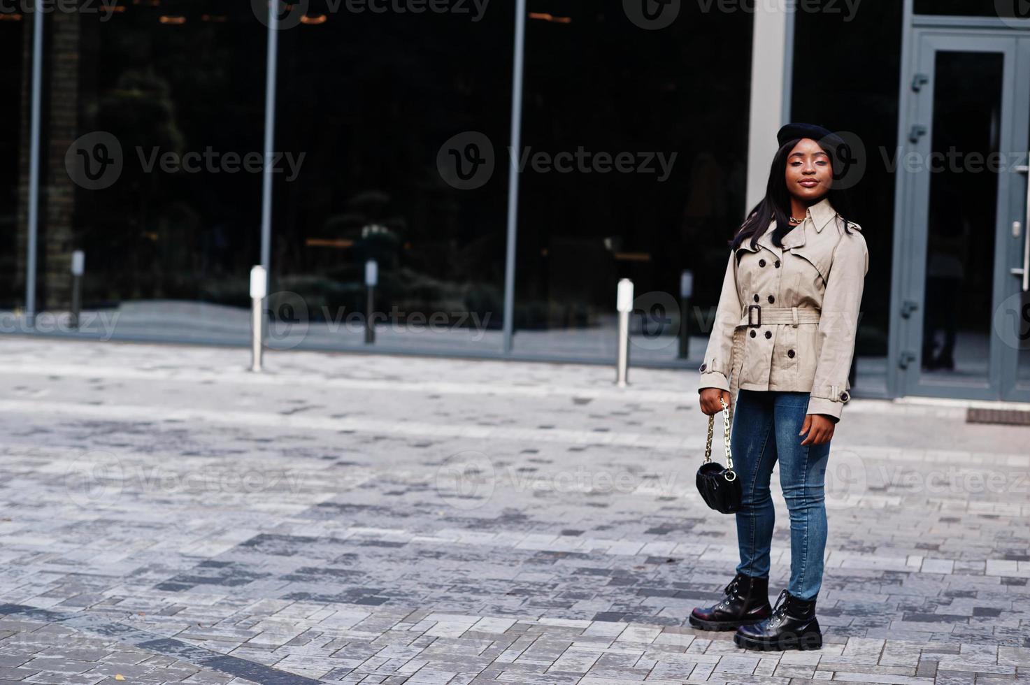 Fashionable african american woman wear beret and coat with handbag posing outdoor. photo