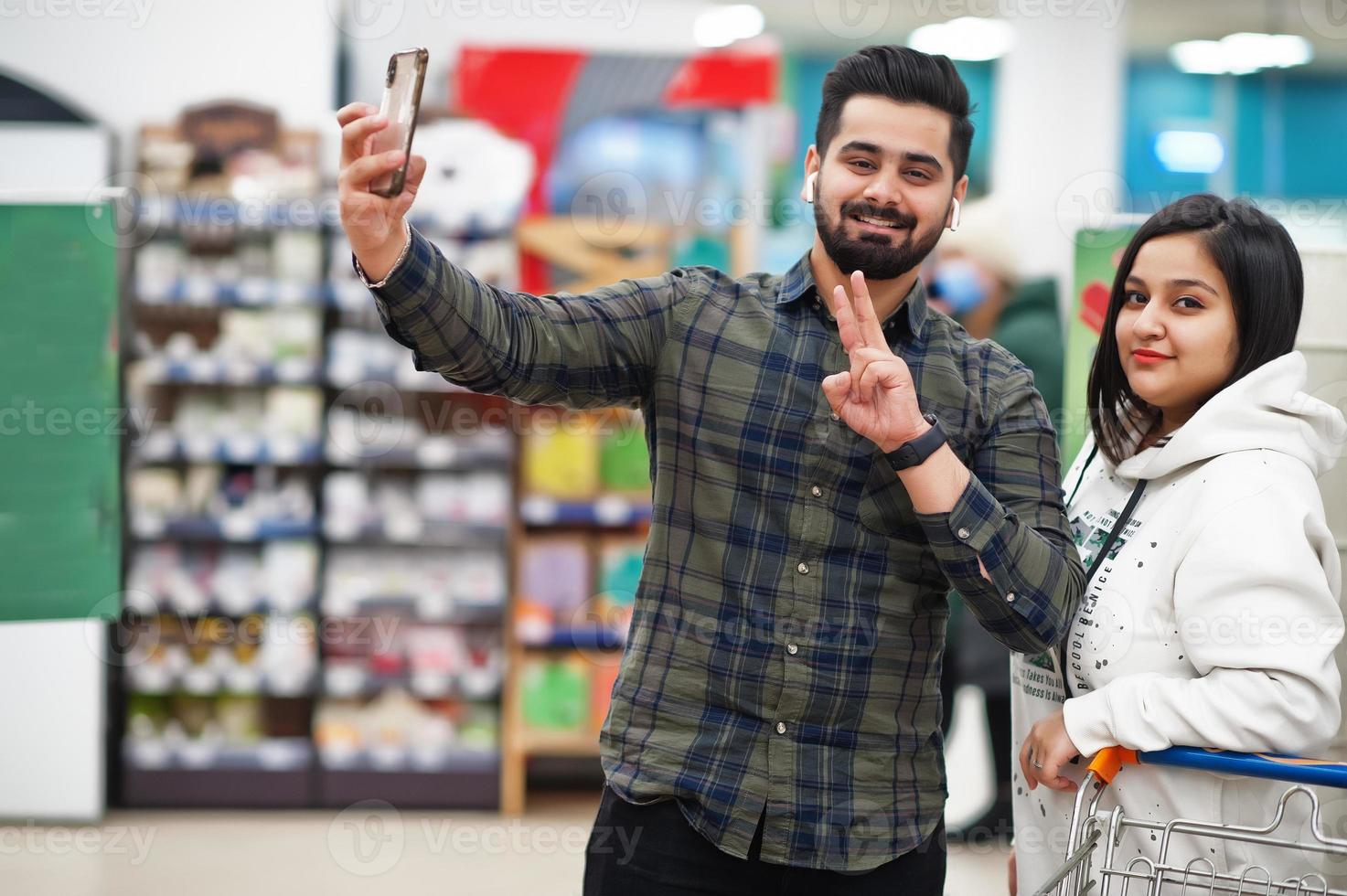 Asian couple wear shopping together in supermarket, making selfie by phone. photo