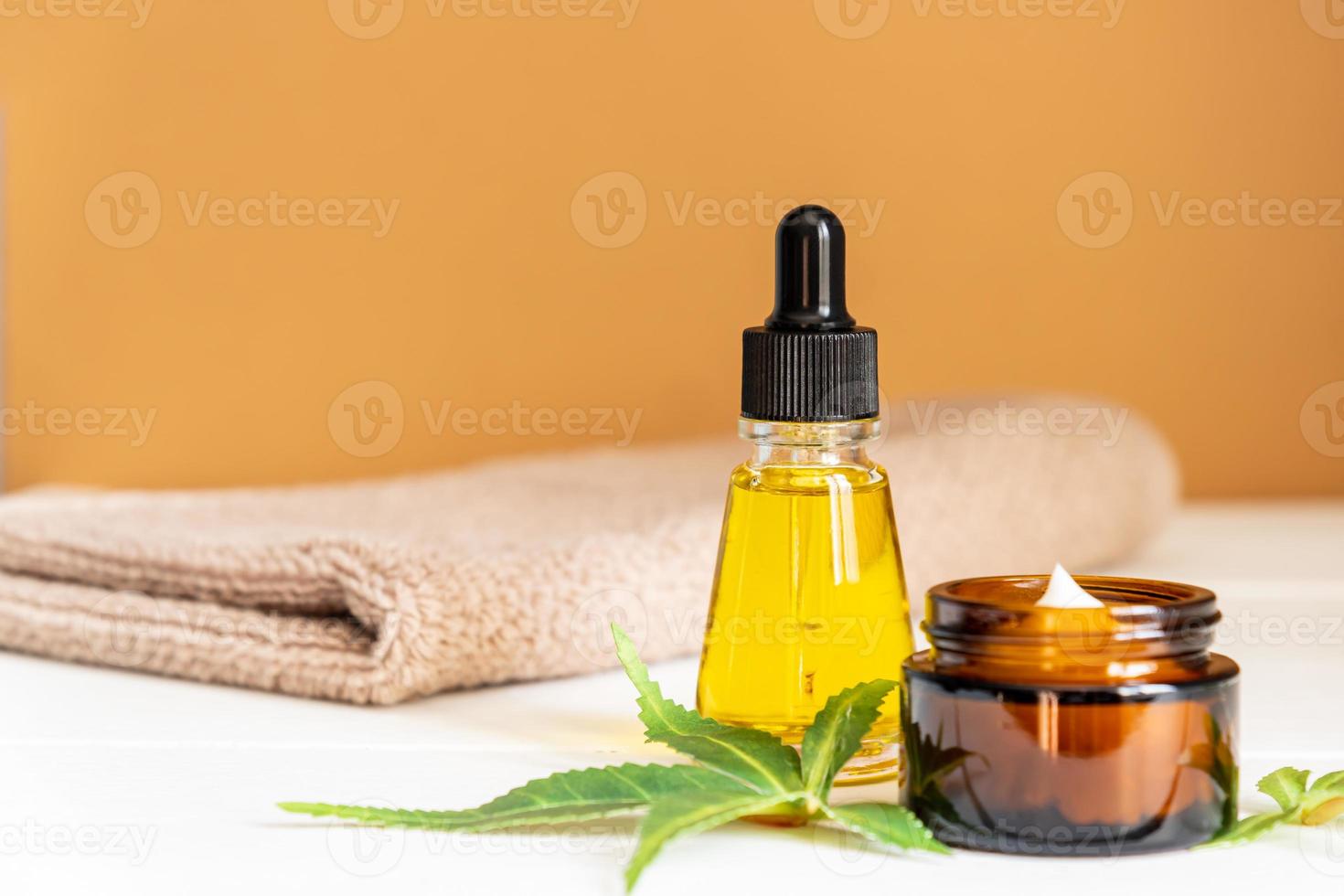 Cannabis face cream or serum or oil dropper concept. Natural cosmetic. CBD oil, THC tincture and hemp leaves on a wooden background photo